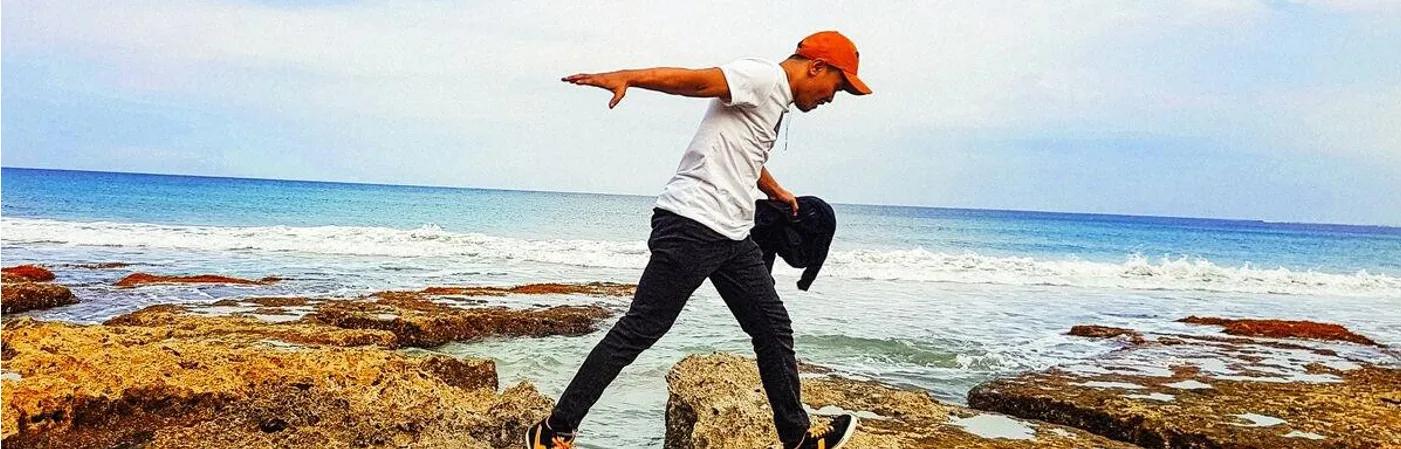 A man crossing between two sea rocks - indicating the missing link between ambition and investment