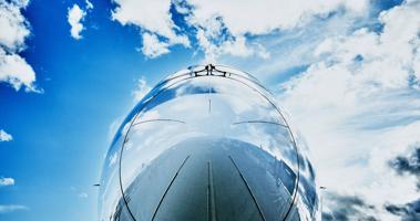 Low angle shot of an airplane's nose against a cloudy blue sky