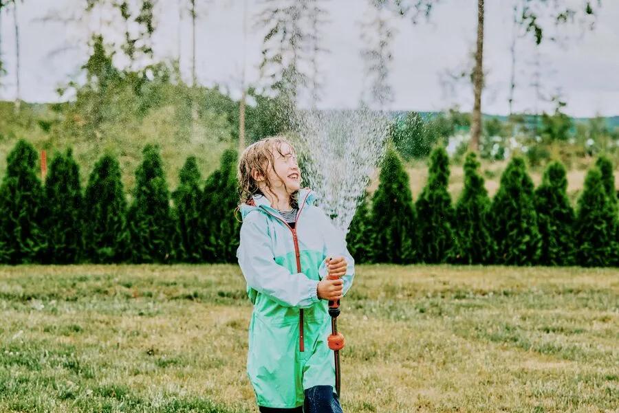 Young girl plays with garden hose